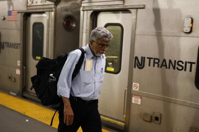 An NJ Transit employee walks on the platform next to a NJ Transit train at New York Penn Station in New York City on April 17, 2026. Football fans have expressed outrage at the exorbitant price of transit fares to get to World Cup matches, following reports that US transport authorities have jacked up prices just for this summer's tournament. New Jersey Transit is planning to charge fans more than $100 for tickets from Penn Station in Manhattan to MetLife Stadium in New Jersey during the World Cup, according to a report in The Athletic. A return ticket for the journey normally costs $12.90. (Photo by CHARLY TRIBALLEAU / AFP)