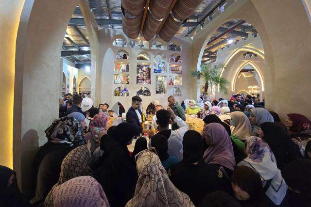 Visitors pause at a stand during the 52nd Tripoli International Fair, which features some 285 local and foreign companies and is drawing large crowds in the Libyan capital, Tripoli on April 17, 2026. (Photo by Mahmud Turkia / AFP)