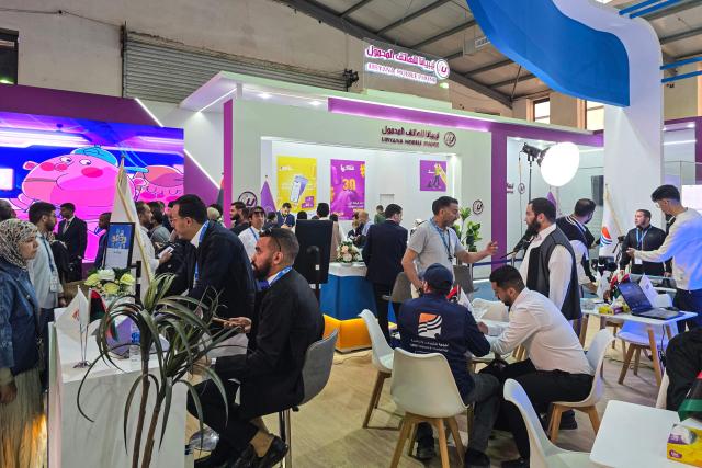 Visitors pause at a stand during the 52nd Tripoli International Fair, which features some 285 local and foreign companies and is drawing large crowds in the Libyan capital, Tripoli on April 17, 2026. (Photo by Mahmud Turkia / AFP)