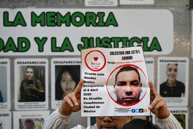 A member of the missing persons search collective “Una Luz en el Camino” displays a photograph of a missing person during a press conference at the so?called Wall of Memory for Truth and Justice, located at the headquarters of the Comprehensive Care Center for the Search for Persons in Mexico City, on April 17, 2026. Several groups searching for missing persons announced this Friday the discovery of more than 1,000 bone fragments in a lakeside area of Mexico City, where Mexican authorities have been conducting excavations for over a week. (Photo by Yuri CORTEZ / AFP)
