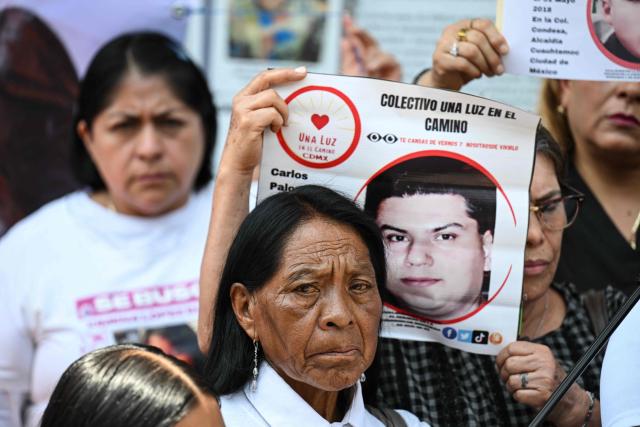A member of the missing persons search collective “Una Luz en el Camino” displays a photograph of a missing person during a press conference at the so?called Wall of Memory for Truth and Justice, located at the headquarters of the Comprehensive Care Center for the Search for Persons in Mexico City, on April 17, 2026. Several groups searching for missing persons announced this Friday the discovery of more than 1,000 bone fragments in a lakeside area of Mexico City, where Mexican authorities have been conducting excavations for over a week. (Photo by Yuri CORTEZ / AFP)