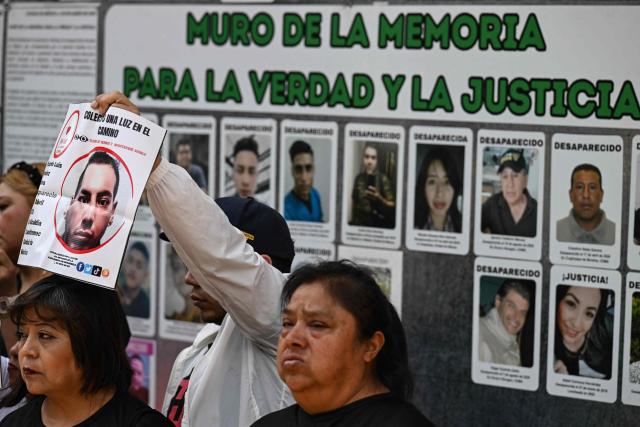 A member of the missing persons search collective “Una Luz en el Camino” displays a photograph of a missing person during a press conference at the so?called Wall of Memory for Truth and Justice, located at the headquarters of the Comprehensive Care Center for the Search for Persons in Mexico City, on April 17, 2026. Several groups searching for missing persons announced this Friday the discovery of more than 1,000 bone fragments in a lakeside area of Mexico City, where Mexican authorities have been conducting excavations for over a week. (Photo by Yuri CORTEZ / AFP)