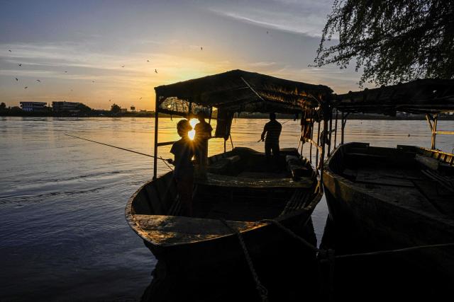 Locals Sudanese residents of Tuti Island, where the White Nile and Blue Nile merge to form the River Nile, stand in a small boat fishing, in Khartoum on April 17, 2026. Of the nearly four million people -- around half Khartoum's pre-war population -- who fled during the conflict, more than 1.8 million have returned over the past year. Yet fewer than 80,000 people have come back to central Khartoum, according to the United Nations. (Photo by Khaled DESOUKI / AFP)