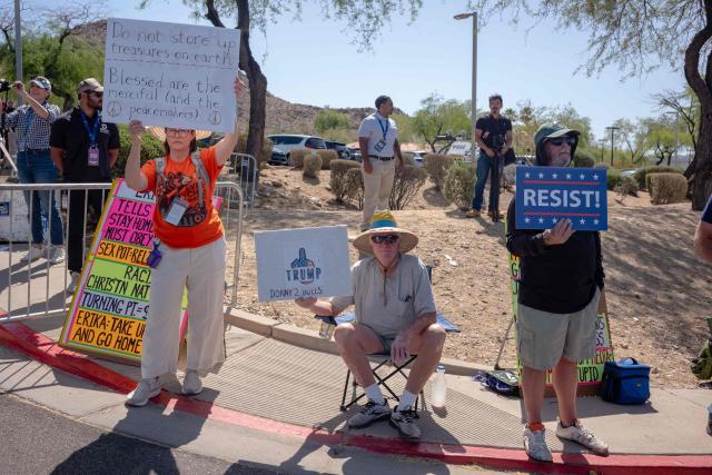 People hold signs as they protest the US president's visit to Arizona outside Dream City Church, where the Turning Point USA "Build the Red Wall" event is being held, in Phoenix, Arizona, on April 17, 2026. President Trump is in Arizona to speak at the Turning Point USA event, the conservative political organization founded by late activist Charlie Kirk. (Photo by Olivier Touron / AFP)