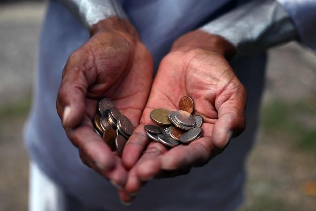 Street performer Samuel Gutierrez, 37, shows the coins he received after juggling sharp metal blades amid midday traffic in San Salvador on April 17, 2026. Samuel says that after ten years in the trade, he has performed on the main streets and avenues of San Salvador, earning between $5 and $10 a day, an income he supplements by selling bracelets and handicrafts he makes himself to cover his family’s expenses. (Photo by Marvin RECINOS / AFP)