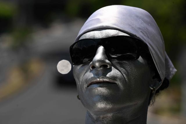 Street performer Samuel Gutierrez, 37, looks on as he waits in the street to juggle sharp metal blades amid midday traffic in San Salvador on April 17, 2026. Samuel says that after ten years in the trade, he has performed on the main streets and avenues of San Salvador, earning between $5 and $10 a day, an income he supplements by selling bracelets and handicrafts he makes himself to cover his family’s expenses. (Photo by Marvin RECINOS / AFP)