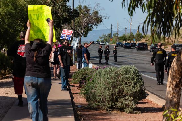 Protesters gesture toward the motorcade of the US president as it leaves via an unexpected exit from where Trump spoke at the Dream City Church, in Phoenix, Arizona, on April 17, 2026. President Trump was in Arizona to speak at the Turning Point USA event, the conservative political organization founded by late activist Charlie Kirk. (Photo by Olivier Touron / AFP)