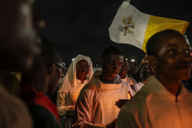 Altar servers hold candles in a procession during a night vigil prayer on the fifth day of Pope Leo XIV’s 11-day apostolic journey to Africa in Yaounde, Cameroon, on April 17, 2026. (Photo by Daniel BELOUMOU OLOMO / AFP)
