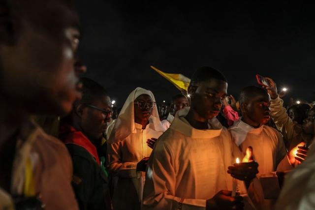 TOPSHOT - Altar servers hold candles in a procession during a night vigil prayer on the fifth day of Pope Leo XIV’s 11-day apostolic journey to Africa in Yaounde, Cameroon, on April 17, 2026. (Photo by Daniel BELOUMOU OLOMO / AFP)