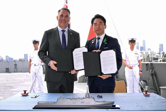Australia's Deputy Prime Minister and Minister for Defence Richard Marles (L) and Japan's Minister of Defense Koizumi Shinjiro pose for a photo after the signing of the contract for Japan to deliver the first three of Mogami-class warships, in Melbourne on April 18, 2026. Japan agreed on April 18 on a deal to provide Australia's navy with the first of almost a dozen stealth frigates, part of a wider military build up by Canberra aimed at boosting its long-range firepower to deter China. (Photo by William WEST / AFP)