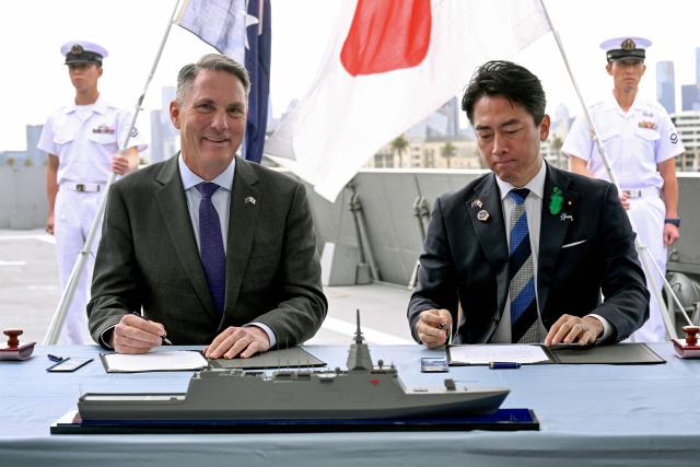 Australia's Deputy Prime Minister and Minister for Defence Richard Marles (L) and Japan's Minister of Defense Koizumi Shinjiro sign the contract for Japan to deliver the first three of Mogami-class warships, in Melbourne on April 18, 2026. Japan agreed on April 18 on a deal to provide Australia's navy with the first of almost a dozen stealth frigates, part of a wider military build up by Canberra aimed at boosting its long-range firepower to deter China. (Photo by William WEST / AFP)