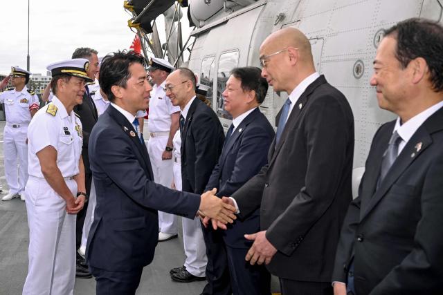 Japan's Minister of Defense Koizumi Shinjiro (L) shakes hands with dignitaries before signing a contract for Japan to deliver the first three of Mogami-class warships to Australia, in Melbourne on April 18, 2026. Japan agreed on April 18 on a deal to provide Australia's navy with the first of almost a dozen stealth frigates, part of a wider military build up by Canberra aimed at boosting its long-range firepower to deter China. (Photo by William WEST / AFP)