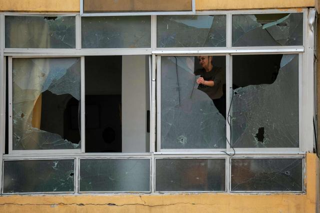 A displaced woman removes shattered glass from the windows of her damaged property in Beirut’s southern suburbs on April 18, 2026. Israel and Lebanon agreed to a 10-day ceasefire on April 16 in order to negotiate an end to six weeks of war between Israel and the Iran-backed group Hezbollah. The conflict saw massive Israeli airstrikes across Lebanon and also a ground invasion in the south. (Photo by ibrahim AMRO / AFP)