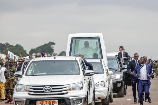 Pope Leo XIV (C) waves from the Popemobile to the crowd as he arrives to lead a Holy Mass at the Yaounde Ville Airport in Yaounde on the sixth day of an 11-day apostolic journey to Africa, on April 18, 2026. (Photo by Patrick MEINHARDT / AFP)
