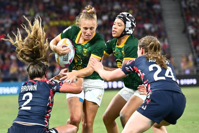 Britain's Abbie Brown (L) and Freya Aucken (R) tackle South Africa's Lerato Makua (2nd-R) and Jane Mulder (2nd-L) on the second day of the 2026 Rugby Sevens Hong Kong tournament at the Kai Tak sports stadium on April 18, 2026. (Photo by Peter PARKS / AFP)