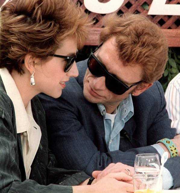 (FILES) French rock star and actor Johnny Hallyday (R) chats with his partner, French actress Nathalie Baye, on May 10 1985, before the screening of his last movie, Detective, directed by Jean-Luc Godard, at Cannes International film festival. Nathalie Baye, 77, passed away on April 17, 2026, announced her family to Agence France-Presse on April 18, 2026. (Photo by Raph GATTI / AFP)