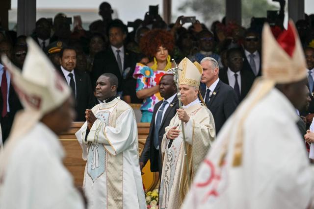 Cameroon's President Paul Biya (2nd L) and Cameroon's First Lady Chantal Biya (C back) watches as Pope Leo XIV (C) arrives to lead the Holy Mass at the Yaounde Ville Airport in Yaounde on the sixth day of an 11-day apostolic journey to Africa, on April 18, 2026. (Photo by Alberto PIZZOLI / AFP)