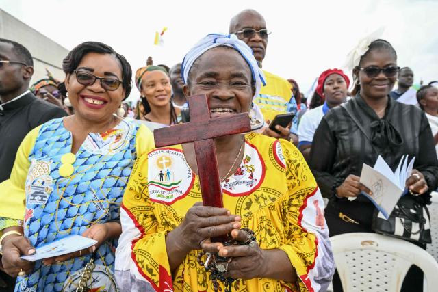 A faithful holds a wooden cross as Pope Leo XIV leads a Holy Mass at the Yaounde Ville Airport in Yaounde on the sixth day of an 11-day apostolic journey to Africa, on April 18, 2026. (Photo by Alberto PIZZOLI / AFP)