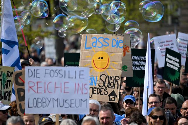 Activists and supporters of Fridays for Future, Campact and other groups hold up placards as they demonstrate against the German government's energy policy, on April 18, 2026 in Berlin. Activists call for faster expansion of solar and wind energy, rapid development of distribution grids, storage and digitalization, a strong European clean energy industry, lower electricity taxes and cheaper power for heat pumps, as well as social support and tenant protection to ensure affordable, climate-friendly heating. (Photo by RALF HIRSCHBERGER / AFP)