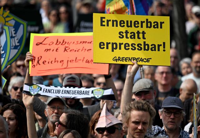 Activists and supporters of Fridays for Future, Campact and other groups hold up placards as they demonstrate against the German government's energy policy, on April 18, 2026 in Berlin. Activists call for faster expansion of solar and wind energy, rapid development of distribution grids, storage and digitalization, a strong European clean energy industry, lower electricity taxes and cheaper power for heat pumps, as well as social support and tenant protection to ensure affordable, climate-friendly heating. (Photo by RALF HIRSCHBERGER / AFP)