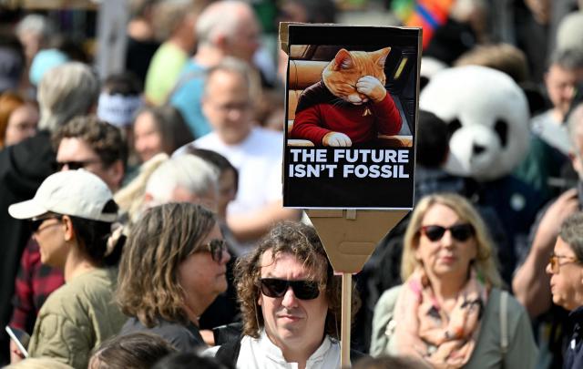 Activists and supporters of Fridays for Future, Campact and other groups hold up placards as they demonstrate against the German government's energy policy, on April 18, 2026 in Berlin. Activists call for faster expansion of solar and wind energy, rapid development of distribution grids, storage and digitalization, a strong European clean energy industry, lower electricity taxes and cheaper power for heat pumps, as well as social support and tenant protection to ensure affordable, climate-friendly heating. (Photo by RALF HIRSCHBERGER / AFP)