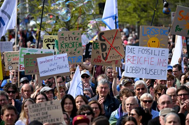 Activists and supporters of Fridays for Future, Campact and other groups hold up placards as they demonstrate against the German government's energy policy, on April 18, 2026 in Berlin. Activists call for faster expansion of solar and wind energy, rapid development of distribution grids, storage and digitalization, a strong European clean energy industry, lower electricity taxes and cheaper power for heat pumps, as well as social support and tenant protection to ensure affordable, climate-friendly heating. (Photo by RALF HIRSCHBERGER / AFP)