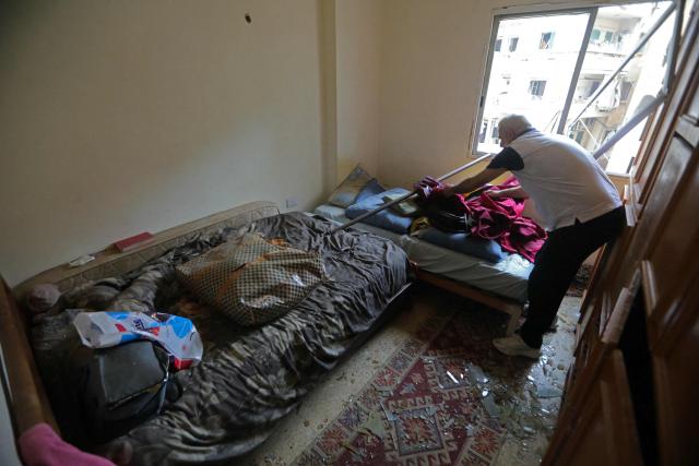 A resident clears the debris from his damaged apartment upon his return to a neighborhood in Beirut’s southern suburbs, on April 18, 2026. Lebanese President Joseph Aoun said on April 17 that his country was on the verge of a "new phase" of "permanent agreements", after the 10-day ceasefire in the Israel-Hezbollah war went into force. Lebanon was drawn into the Middle East conflict on March 2 when Tehran-backed Hezbollah attacked Israel to avenge the death of Iranian supreme leader Ali Khamenei. (Photo by Ibrahim AMRO / AFP) / 