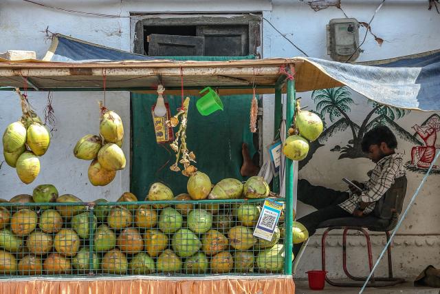 A vendor selling coconut water waits for customers at his roadside stall along a street on a hot summer day in Varanasi on April 18, 2026. (Photo by Niharika KULKARNI / AFP)