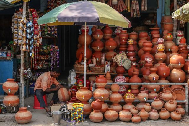 A vendor works on earthen water pots as he sits under a shelter waiting for customers along a street on a hot summer day in Varanasi on April 18, 2026. (Photo by Niharika KULKARNI / AFP)