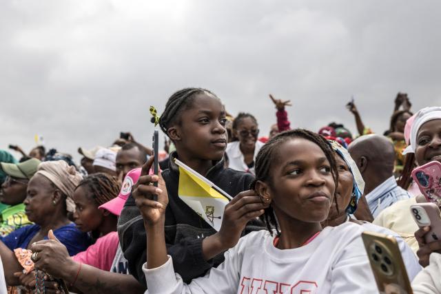 Faithfuls watch as Pope Leo XIV (unseen) waves from the Popemobile to the crowd as he arrives to lead a Holy Mass at the Yaounde Ville Airport in Yaounde on the sixth day of an 11-day apostolic journey to Africa, on April 18, 2026. (Photo by PATRICK MEINHARDT / AFP)