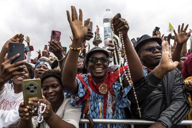 Faithfuls cheer as they watch Pope Leo XIV (unseen) waves from the Popemobile to the crowd as he arrives to lead a Holy Mass at the Yaounde Ville Airport in Yaounde on the sixth day of an 11-day apostolic journey to Africa, on April 18, 2026. (Photo by PATRICK MEINHARDT / AFP)