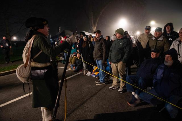 A Lexington Minute Men reenactor speaks to members of the public before the start of a reenactment of the Battle of Lexington and Concord as part of Patriot's Day celebrations in Lexington, Massachusetts, on April 18, 2026. April 19, 2026 marks the 250th anniversary of the Battle of Lexington and Concord, the first major military actions between the British Army and the Colonial American militias during the American Revolutionary War. (Photo by Joseph Prezioso / AFP)