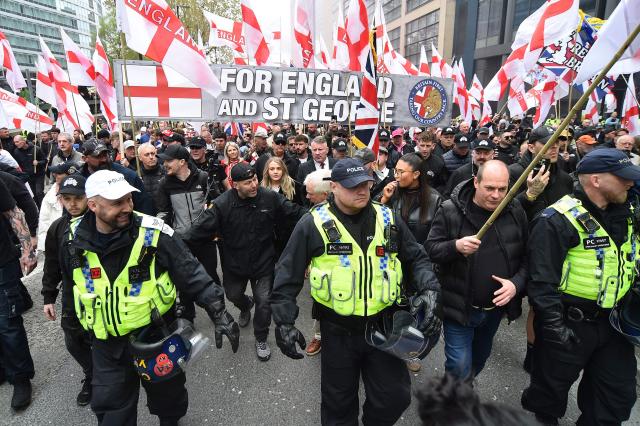 Leader of Britain First, Paul Golding (C) walks alongside people waving Union Jack and St George’s cross flags during a Britain First march in Manchester on April, 18, 2026. (Photo by PETER POWELL / AFP)