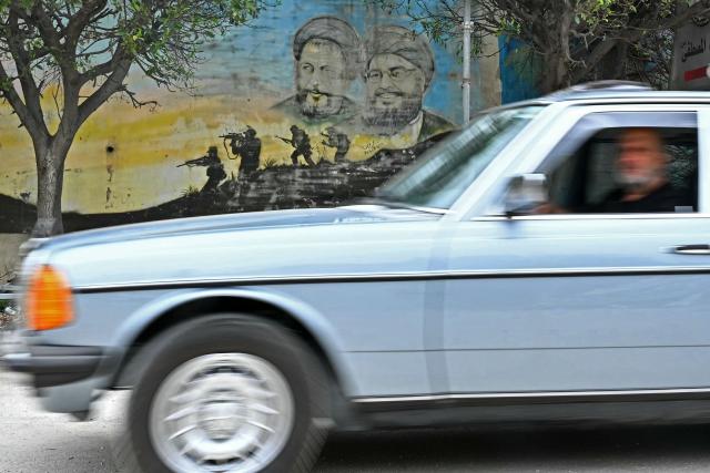 Displaced residents drive past a wall mural of Hezbollah leaders as they return back to the southern Lebanese city of Nabatieh on April 18, 2026. Lebanese President Joseph Aoun said on April 17 that his country was on the verge of a "new phase" of "permanent agreements", after the 10-day ceasefire in the Israel-Hezbollah war went into force. Lebanon was drawn into the Middle East conflict on March 2 when Tehran-backed Hezbollah attacked Israel to avenge the death of Iranian supreme leader Ali Khamenei. (Photo by FADEL itani / AFP)