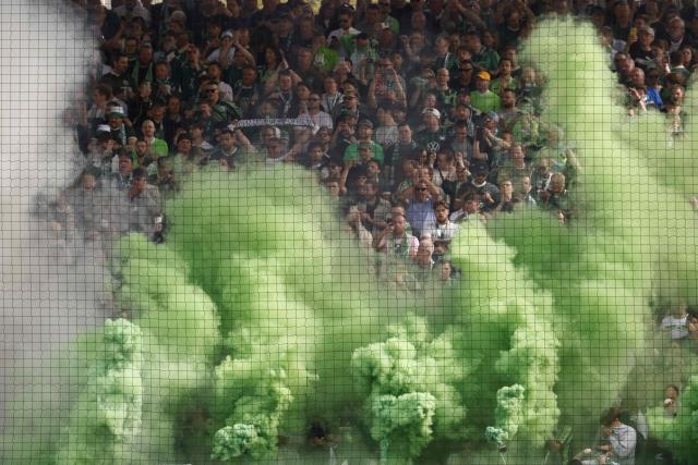 Green smoke clouds raise from flares on the terraces among supporters of VfL Wolfsburg prior to the start of the German first division Bundesliga football match between Union Berlin and VfL Wolfsburg in Berlin, Germany, on April 18, 2026. (Photo by Odd ANDERSEN / AFP) / DFL REGULATIONS PROHIBIT ANY USE OF PHOTOGRAPHS AS IMAGE SEQUENCES AND/OR QUASI-VIDEO