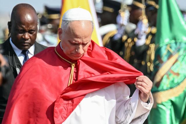 Pope Leo XIV fixes his pellegrina as he arrives at the "4 de Fevereiro" Luanda International Airport in Luanda on the sixth day of an 11-day apostolic journey to Africa, on April 18, 2026. (Photo by Alberto PIZZOLI / AFP)