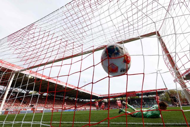 Wolfsburg's scores the opening 0-1 goal past Union Berlin's Danish goalkeeper #01 Frederik Ronnow (R) during the German first division Bundesliga football match between Union Berlin and VfL Wolfsburg in Berlin, Germany, on April 18, 2026. (Photo by Odd ANDERSEN / AFP) / DFL REGULATIONS PROHIBIT ANY USE OF PHOTOGRAPHS AS IMAGE SEQUENCES AND/OR QUASI-VIDEO