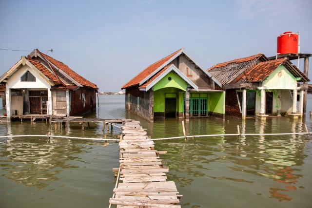 Houses remain partially submerged in seawater due to tidal flooding at the Timbulsloko village in Demak, Central Java on April 18, 2026. (Photo by DEVI RAHMAN / AFP)