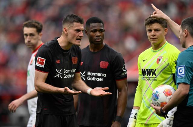 Bayer Leverkusen's Czech forward #14 Patrik Schick (L) discusses with the referee during the German first division Bundesliga football match between Bayer 04 Leverkusen and FC Augsburg in Leverkusen, western Germany, on April 18, 2026. (Photo by INA FASSBENDER / AFP) / DFL REGULATIONS PROHIBIT ANY USE OF PHOTOGRAPHS AS IMAGE SEQUENCES AND/OR QUASI-VIDEO