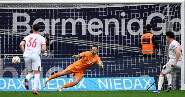 Augsburg's Swiss midfielder #32 Fabian Rieder (R) shoots the ball to score the 1-2 goal against Bayer Leverkusen's Dutch goalkeeper #01 Mark Flekken (C) during the German first division Bundesliga football match between Bayer 04 Leverkusen and FC Augsburg in Leverkusen, western Germany, on April 18, 2026. (Photo by INA FASSBENDER / AFP) / DFL REGULATIONS PROHIBIT ANY USE OF PHOTOGRAPHS AS IMAGE SEQUENCES AND/OR QUASI-VIDEO