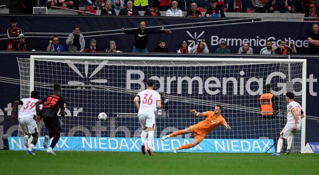 Augsburg's Swiss midfielder #32 Fabian Rieder (R) shoots the ball to score the 1-2 goal against Bayer Leverkusen's Dutch goalkeeper #01 Mark Flekken (2nd R) during the German first division Bundesliga football match between Bayer 04 Leverkusen and FC Augsburg in Leverkusen, western Germany, on April 18, 2026. (Photo by INA FASSBENDER / AFP) / DFL REGULATIONS PROHIBIT ANY USE OF PHOTOGRAPHS AS IMAGE SEQUENCES AND/OR QUASI-VIDEO