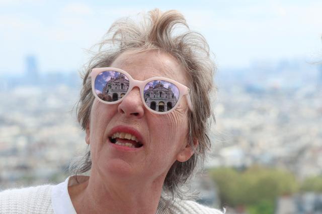 The Sacre-Coeur Basilica is seen reflected on the sunglasses of a tourist in Paris on April 18, 2026. (Photo by ALAIN JOCARD / AFP)