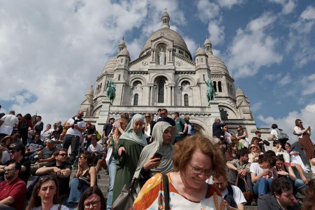 Tourists sit and walk on the steps of the Sacre-Coeur Basilica in Paris on April 18, 2026. (Photo by ALAIN JOCARD / AFP)