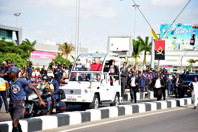 Faithfuls cheer as Pope Leo XIV (C) waves at them from the Popemobile after his arrival at the "4 de Fevereiro" Luanda International Airport in Luanda on the sixth day of an 11-day apostolic journey to Africa, on April 18, 2026. (Photo by Julio PACHECO NTELA / AFP)