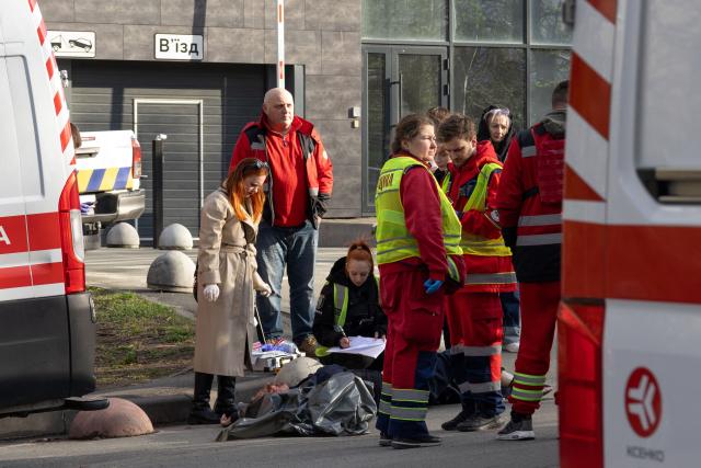 EDITORS NOTE: Graphic content / Police experts examine a body of a person shot by a gunman outside a supermarket in Kyiv on April 18, 2026. A gunman opened fire in Kyiv on April 18, 2026, killing at least five people, wounding others and taking hostages at a supermarket before being killed during an arrest attempt, officials said. Ukrainian President said that at least five people were dead and 10 hospitalised with wounds and trauma after the shooting in a residential district of the capital. (Photo by Serhii Okunev / AFP)