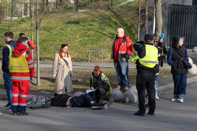 EDITORS NOTE: Graphic content / TOPSHOT - Police experts examine a body of a person shot by a gunman outside a supermarket in Kyiv on April 18, 2026. A gunman opened fire in Kyiv on April 18, 2026, killing at least five people, wounding others and taking hostages at a supermarket before being killed during an arrest attempt, officials said. Ukrainian President said that at least five people were dead and 10 hospitalised with wounds and trauma after the shooting in a residential district of the capital. (Photo by Serhii Okunev / AFP)