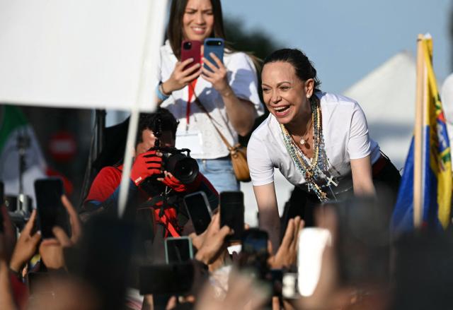 Venezuelan opposition leader Maria Corina Machado greets supporters on stage in Madrid's Puerta del Sol on April 18, 2026. Spain's right-wing parties showed their support for Venezuelan opposition figure and Nobel Peace Prize winner Maria Corina Machado who  turned down a meeting with the country's leftist PM, considering it 'unsuitable' for the moment. (Photo by Javier SORIANO / AFP)