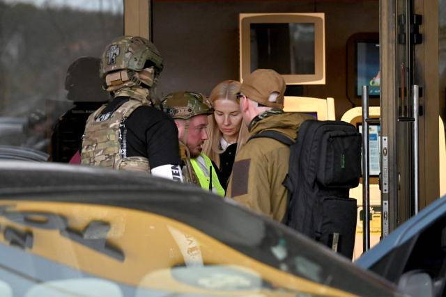 Policemen pull away a saleswoman from a supermarket after a shooting in Kyiv on April 18, 2026. A gunman opened fire in Kyiv on April 18, 2026, killing at least five people, wounding others and taking hostages at a supermarket before being killed during an arrest attempt, officials said. Ukrainian President said that at least five people were dead and 10 hospitalised with wounds and trauma after the shooting in a residential district of the capital. (Photo by Sergei SUPINSKY / AFP)
