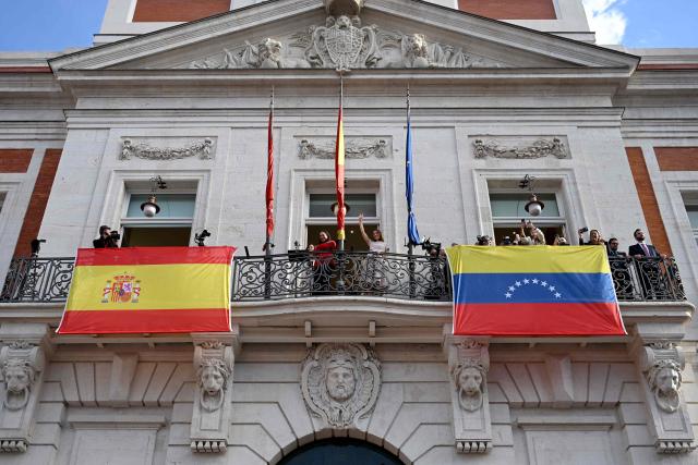 Venezuelan opposition leader Maria Corina Machado, flanked by Madrid's regional president Isabel Ayuso (C,L) and Venezuelan opposition Edmundo Gonzalez' daughter Carolina Gonzalez (C,R), waves to supporters in Madrid's Puerta del Sol on April 18, 2026. Spain's right-wing parties showed their support for Venezuelan opposition figure and Nobel Peace Prize winner Maria Corina Machado who  turned down a meeting with the country's leftist PM, considering it 'unsuitable' for the moment. (Photo by JAVIER SORIANO / AFP)