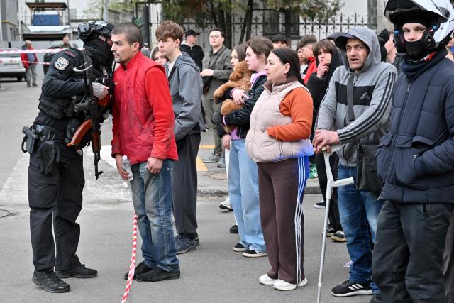 People stand outside a supermarket following a shooting in Kyiv on April 18, 2026. A gunman opened fire in Kyiv on April 18, 2026, killing at least five people, wounding others and taking hostages at a supermarket before being killed during an arrest attempt, officials said. Ukrainian President said that at least five people were dead and 10 hospitalised with wounds and trauma after the shooting in a residential district of the capital. (Photo by Sergei SUPINSKY / AFP)